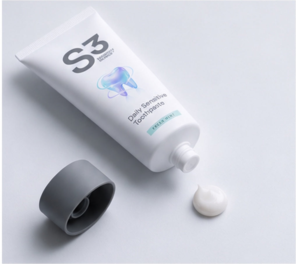 An open tube of S3 Daily Sensitive Toothpaste lying flat beside its cap and a small dab of paste